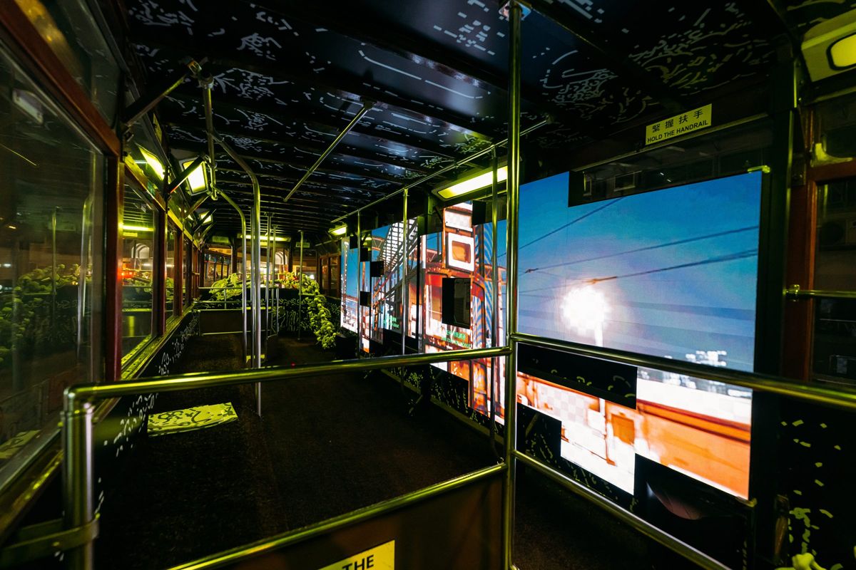 The upper deck with screens showing Hong Kong street scenes.