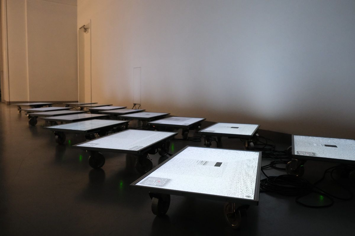 Trolleys with screens spread across a dark gallery floor.