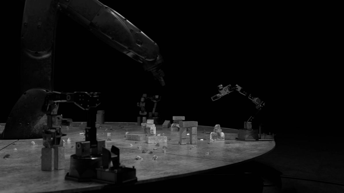 Small robot arms placing blocks on the table, the industrial arm looming behind.