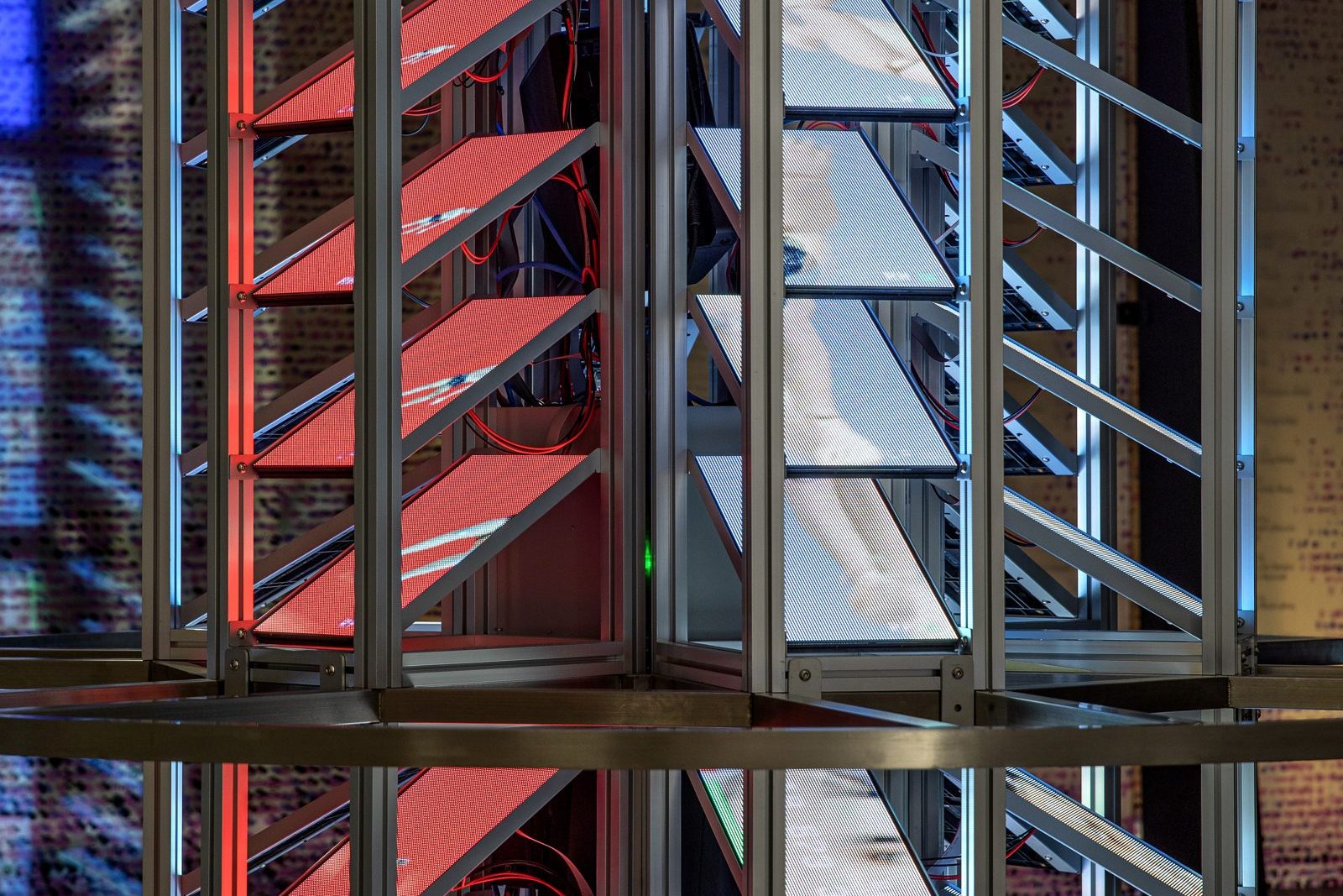 Detail of the tower: aluminium frames holding rows of angled screens glowing red and white.